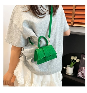 Green quilted mini handbag with top handle and shoulder strap shown in a lifestyle setting