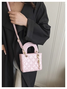 Detail of pink quilted patent leather mini bag with gold hardware worn on black trench coat