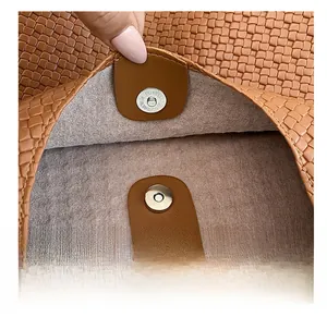 Close-up of the metal magnetic clasp and woven texture of the caramel tote bag