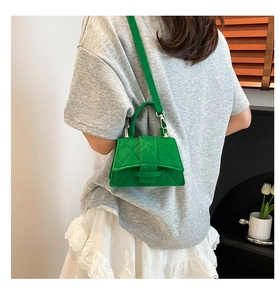 Detail view of a green quilted mini crossbody bag with golden hardware and top handle