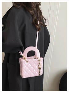 Mini borsa trapuntata rosa con dettagli dorati indossata su un trench nero