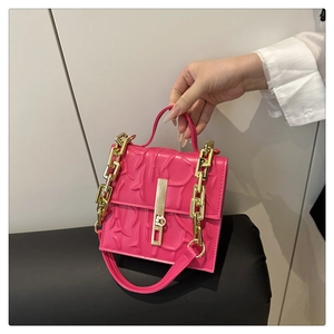 Detail of rose pink handbag with embossed pattern and chunky gold chain strap