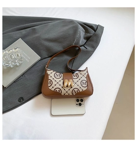 Detail of vintage canvas baguette bag with golden M-shaped clasp and brown leather trim