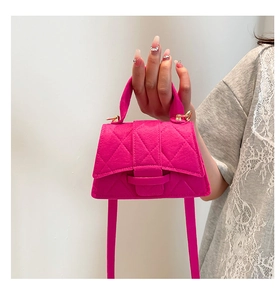 Detail of fuchsia felt handbag featuring diamond quilting and gold metallic buckle closure