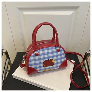 Detail of red leather trim on plaid canvas bag with apple print and silver metal hardware