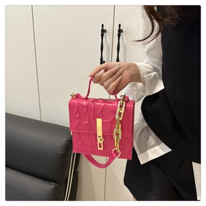 Detail of rose red bag featuring 3D embossed texture and gold metal chain link