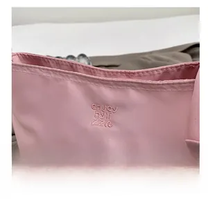 Close-up of light pink fabric handbag featuring detailed embroidery with smooth stitching
