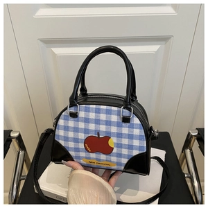 Detailed view of blue plaid crossbody bag with apple print and black leather handles
