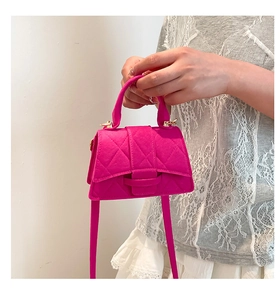 Macro shot of fuchsia quilted handbag with gold hardware and elegant handle detail