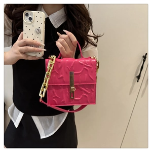 Detail of rose pink embossed leather crossbody bag with gold chain and square lock closure