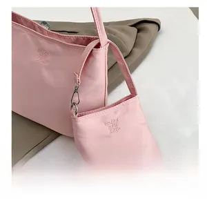 Detailed view of pink nylon shoulder bag set with small pouch and embroidery details