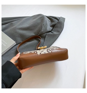 Detail of vintage canvas baguette bag with brown leather trim and golden metal clasp