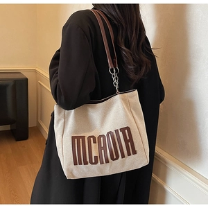 Detailed macro view of the 3D MCAOIR letter logo and metal chain on canvas tote bag