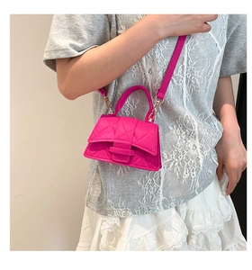 Detail of fuchsia quilted crossbody mini bag showing hourglass shape and texture