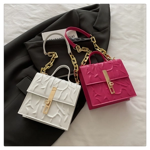 Detail of square chain bag showing embossed texture and golden metal lock hardware