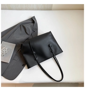 Close-up of minimalist black matte leather tote bag with slender straps for business commute