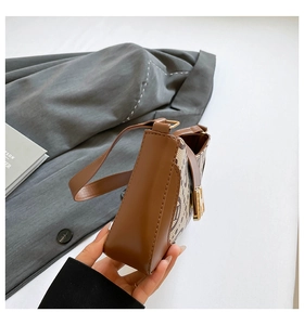 Detailed view of monogram fabric underarm bag with gold H-shaped buckle and leather trim
