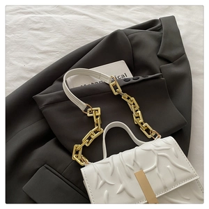 Detail of white embossed floral texture handbag with gold metal clasp and chain strap