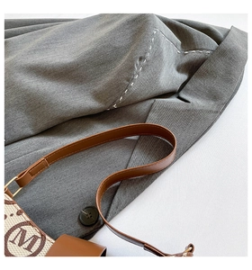 Detailed shot of retro printed baguette bag with M-pattern leather strap and white stitching