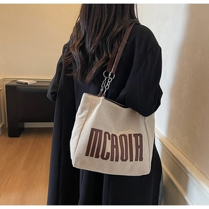 Detail of the durable canvas tote bag featuring leather chain straps and MCADIR lettering
