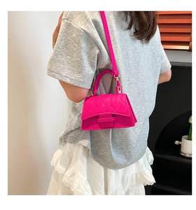 Close-up of bright pink quilted mini handbag with top handle worn on model