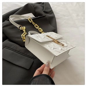 Detail of white square bag featuring geometric texture and gold chunky chain strap