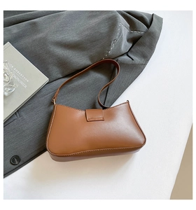 Close-up of brown matte leather baguette bag on grey suit fabric for professional styling