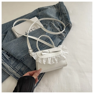Dettaglio della mini borsa bianca con delicato ricamo in pizzo e fiocco decorativo