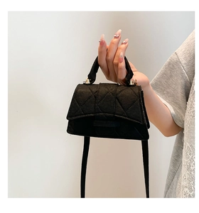 Close-up of black felt crossbody bag featuring quilted rhombus pattern and gold metal hardware