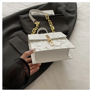Detail of white structured handbag with 3D embossed branch texture and gold chain strap