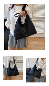 Detail of a large black woven hobo tote bag featuring fine leather texture and wide strap