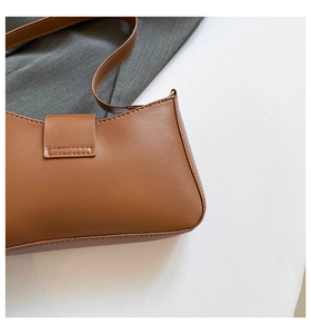 Detail of vintage brown leather baguette bag featuring smooth texture and flap closure