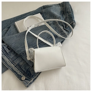 Dettaglio della mini borsa bianca con bordo in pizzo e tracolla sottile in pelle