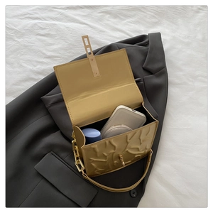 Detail of light brown embossed shoulder bag interior holding phone and makeup