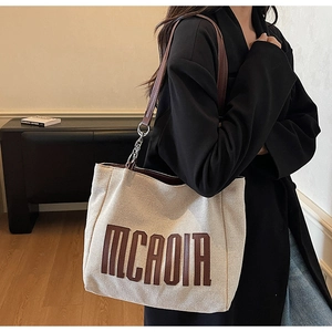 Detail of canvas tote bag featuring premium leather strap and silver metal chain link