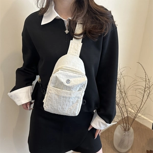 Waterproof off-white nylon chest bag with adjustable strap shown on female model