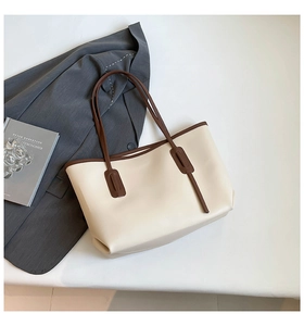 Close-up of a large beige and brown contrast leather tote bag with long shoulder straps