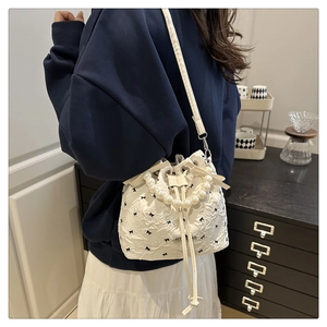 Sac seau blanc chic avec poignée en perles et détails de broderie nœuds noirs sur modèle