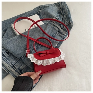 Dettaglio mini borsa rossa con fiocco e pizzo bianco sopra una giacca di denim