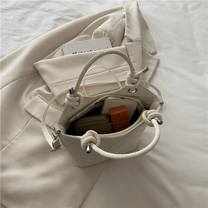 Sac seau minimaliste en cuir beige avec poignée torsadée et intérieur spacieux