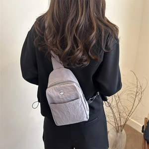Minimalist light grey waterproof nylon chest bag with metallic logo on a casual model
