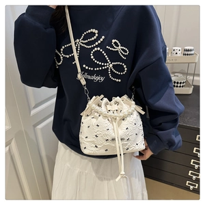 Vue détaillée du sac seau blanc avec broderie nœuds noirs et poignée en perles