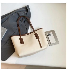 Detailed view of large cream tote bag with dark brown handles and urban commute accessories