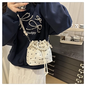 Détail d'un sac seau blanc avec broderie de nœuds noirs et anse en perles élégante