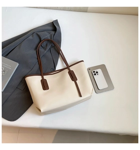 Minimalist large tote bag with brown trim shown next to business accessories and books