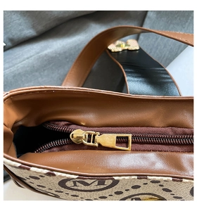 Detail view of smooth brown zipper and gold hardware on vintage letter print baguette bag