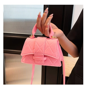 Detailed close-up of pink felt handbag featuring diamond stitching and gold buckles
