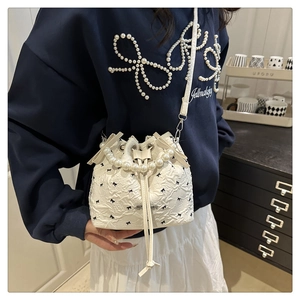 Détail du sac seau blanc avec broderie nœud noir et poignée élégante en perles