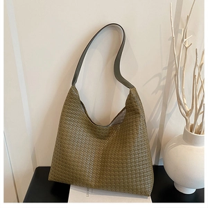 Detail of olive green woven leather tote bag texture and smooth gray shoulder strap