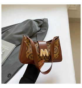 Detail of vintage baguette bag featuring M-pattern canvas and gold metallic logo buckle